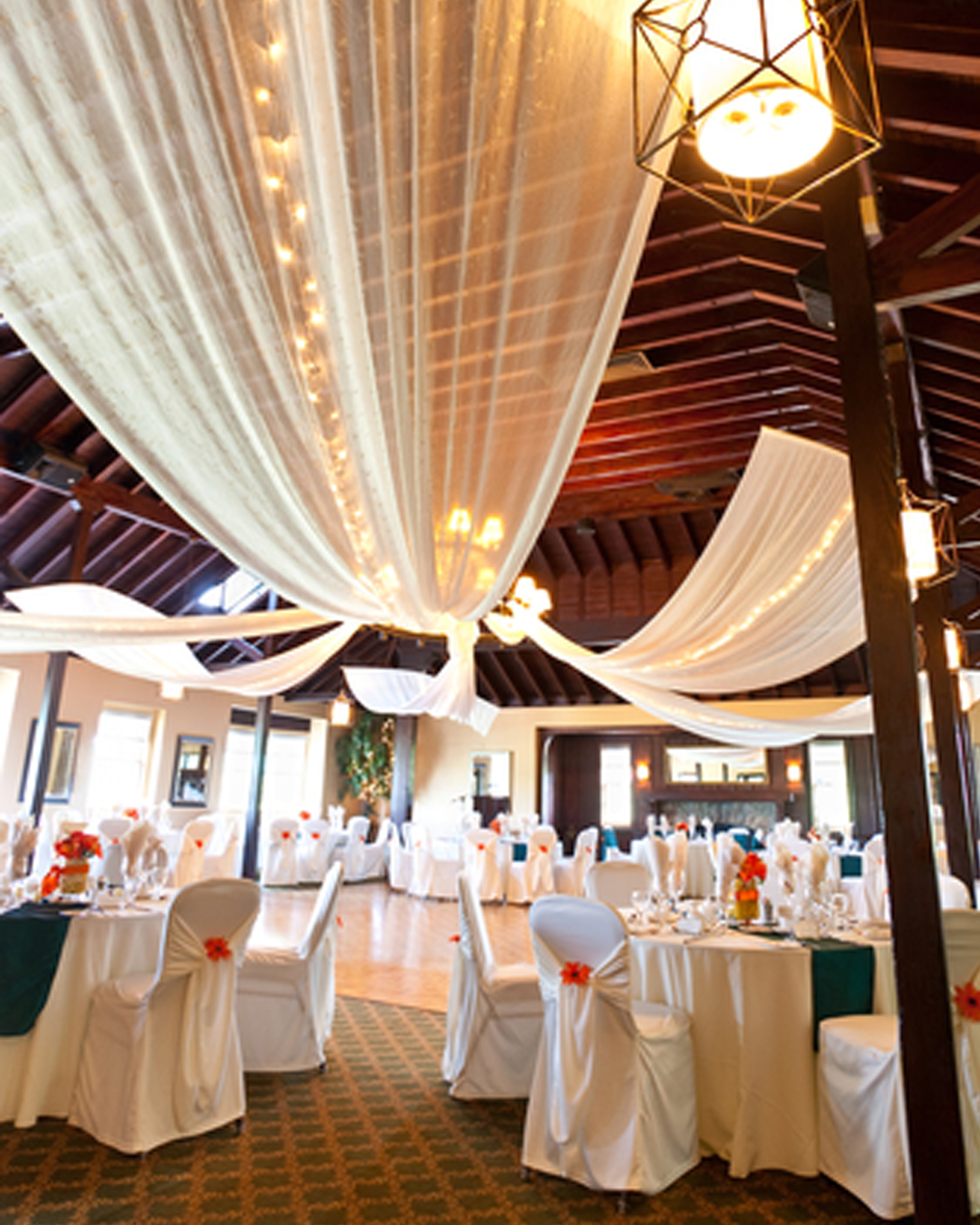 Visual Display Production 3 a wedding venue table arrangement. With ivory ceiling drapes and ivory chair covers. The table is set ready for the guests.